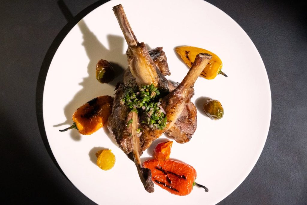 Rack de Cordero de Colorado con mini pimientos y gremolata de hierbas en Harry’s Prime Steakhouse & Raw Bar.